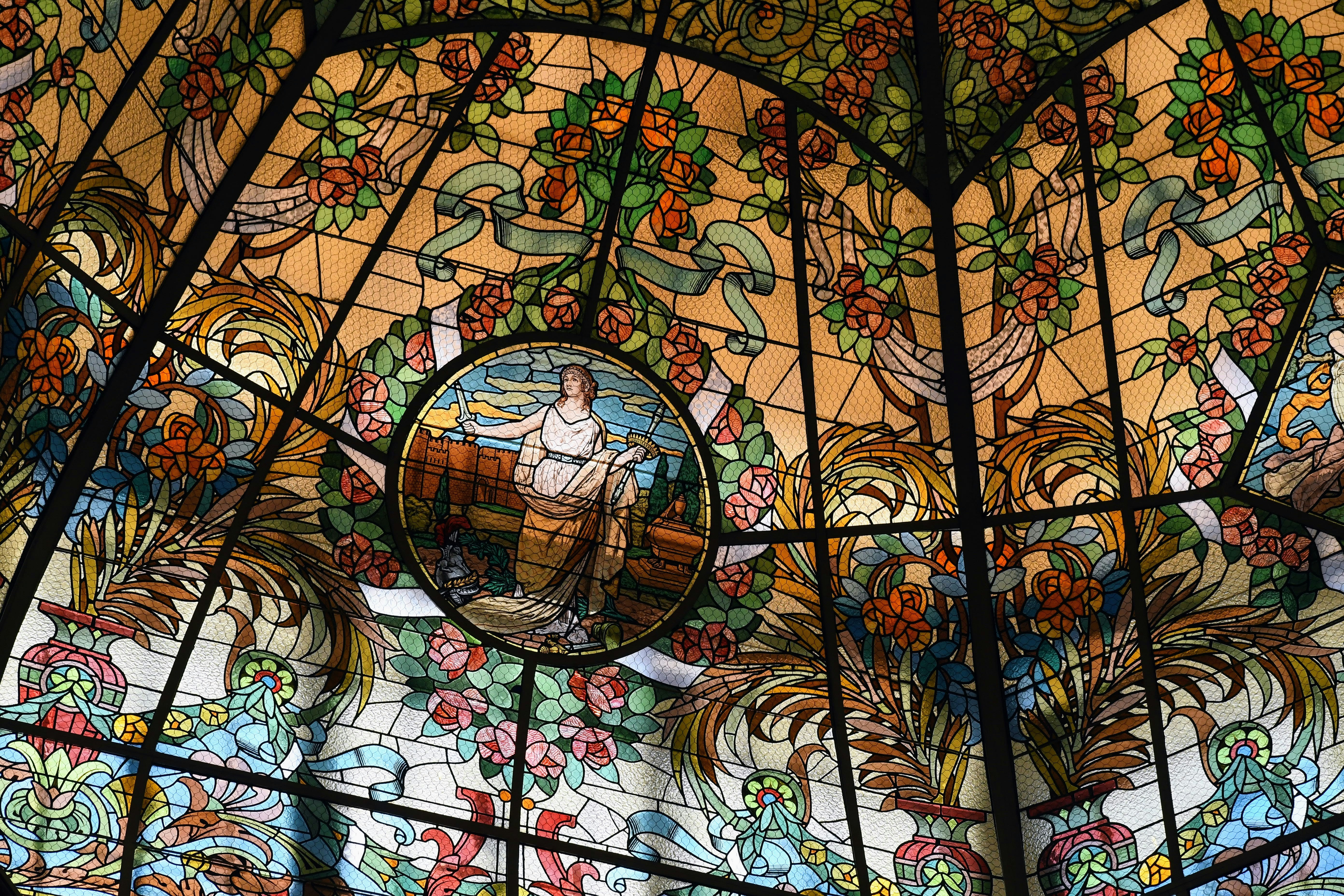 Beautiful stained glass dome with floral and figure designs.