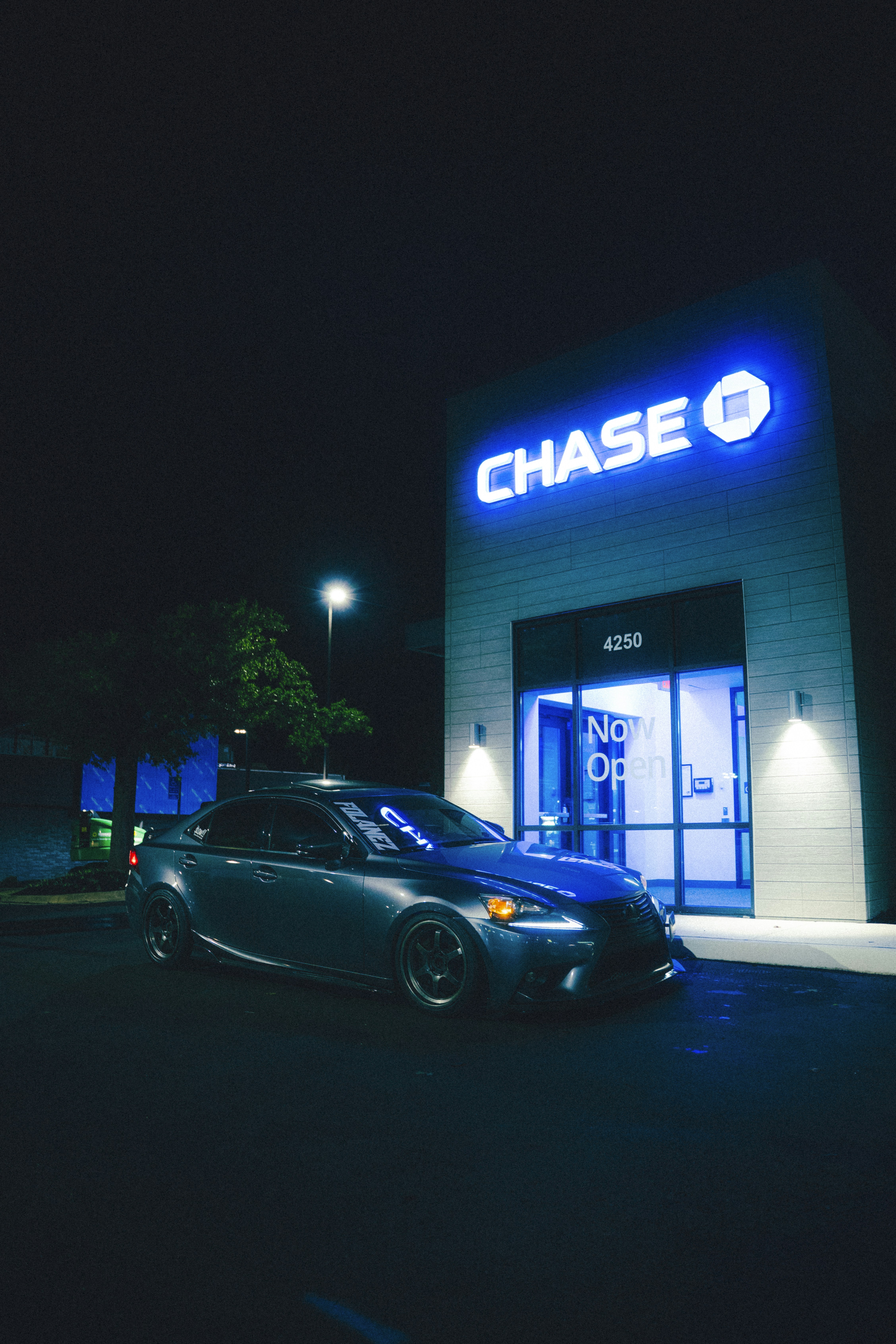 A car is parked outside a chase bank at night.
