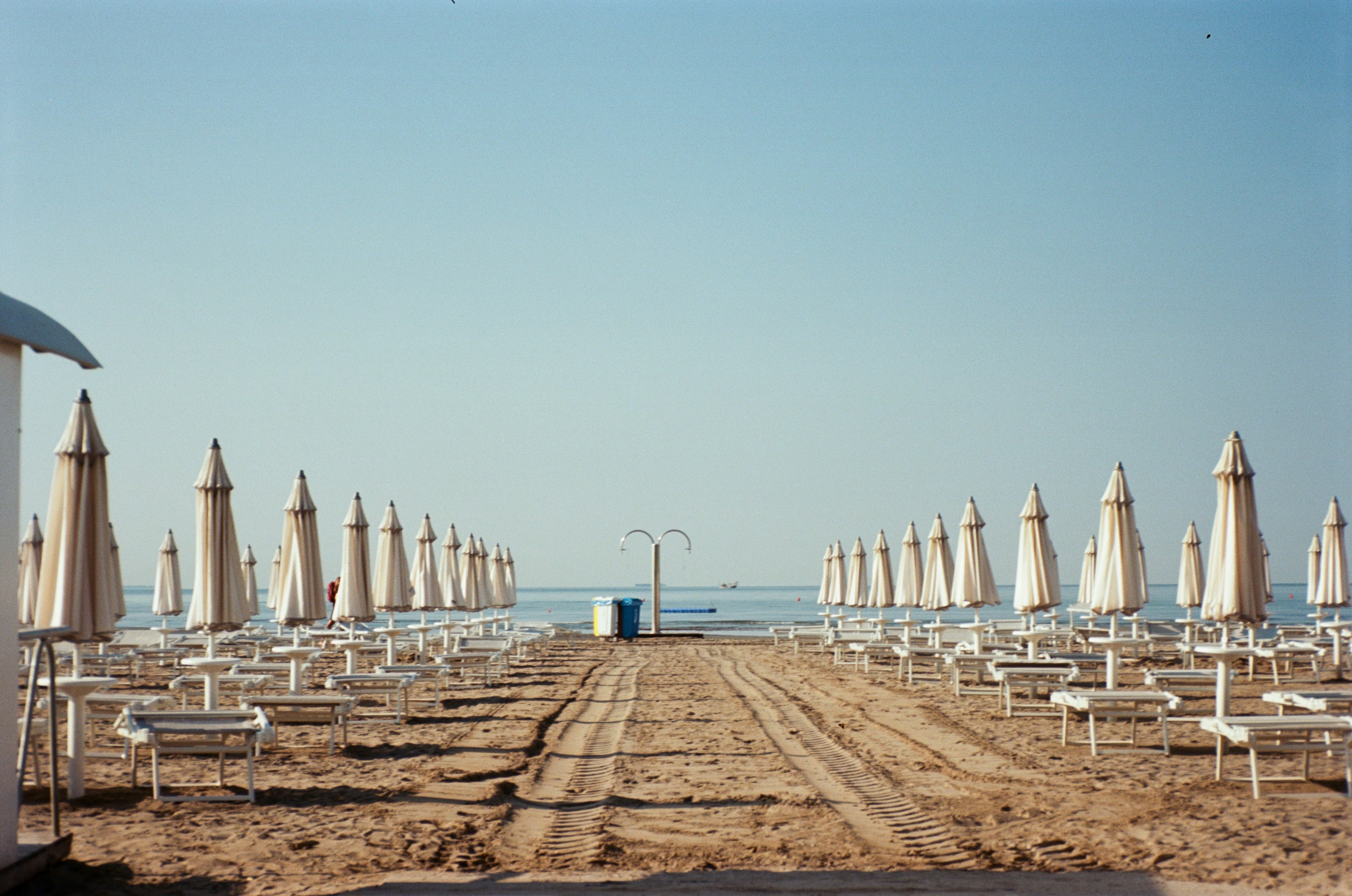 Closed umbrellas line a beach on a sunny day.