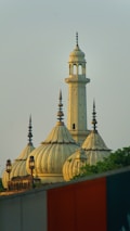 A mosque's domes and minaret against a clear sky.
