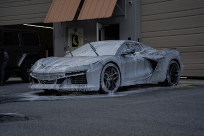 A corvette is being washed with foamy soap.