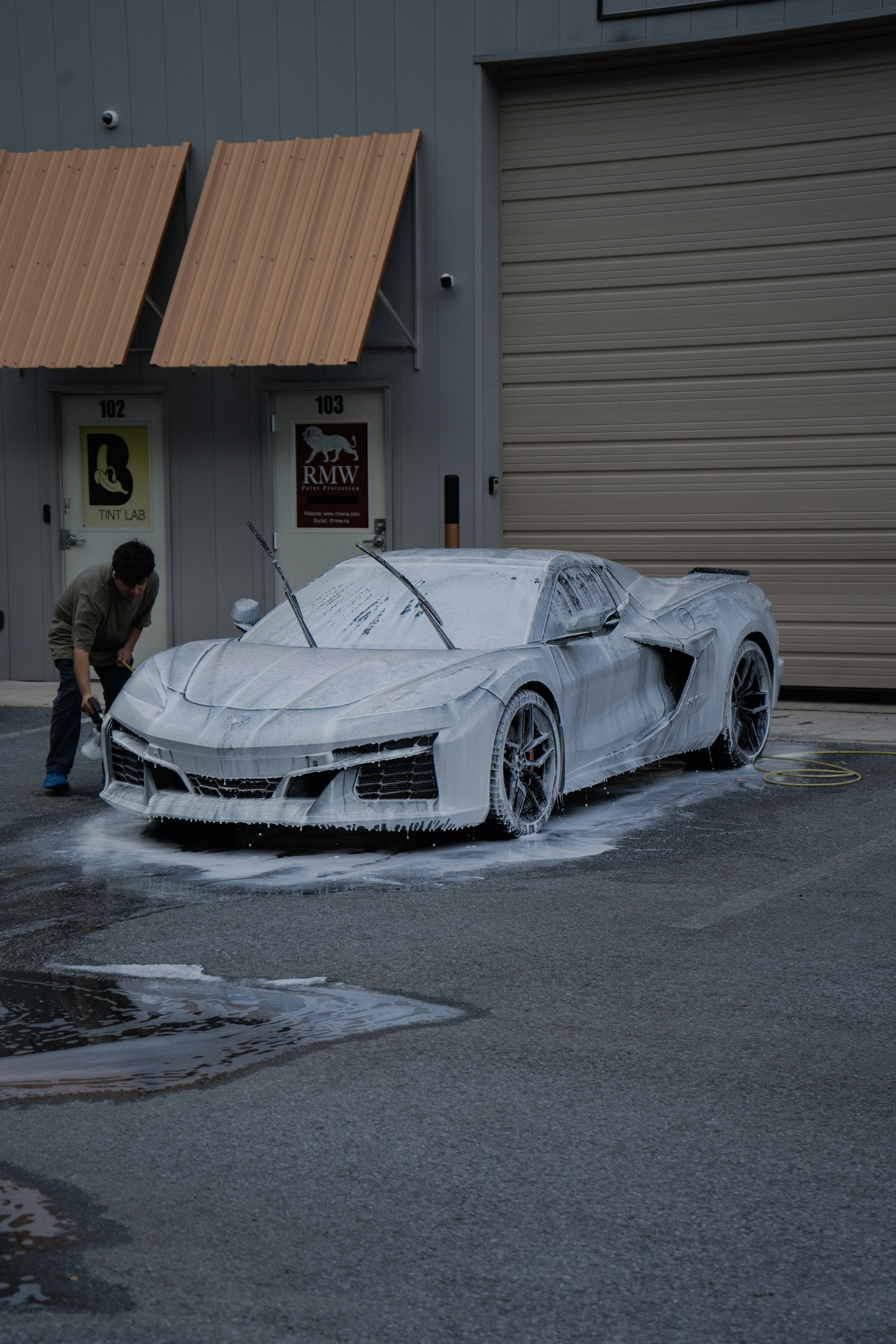 A man washes a car covered in soapy foam.