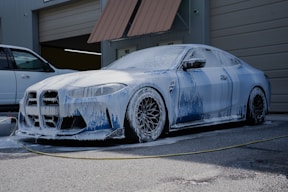 A blue car is covered in soap suds.