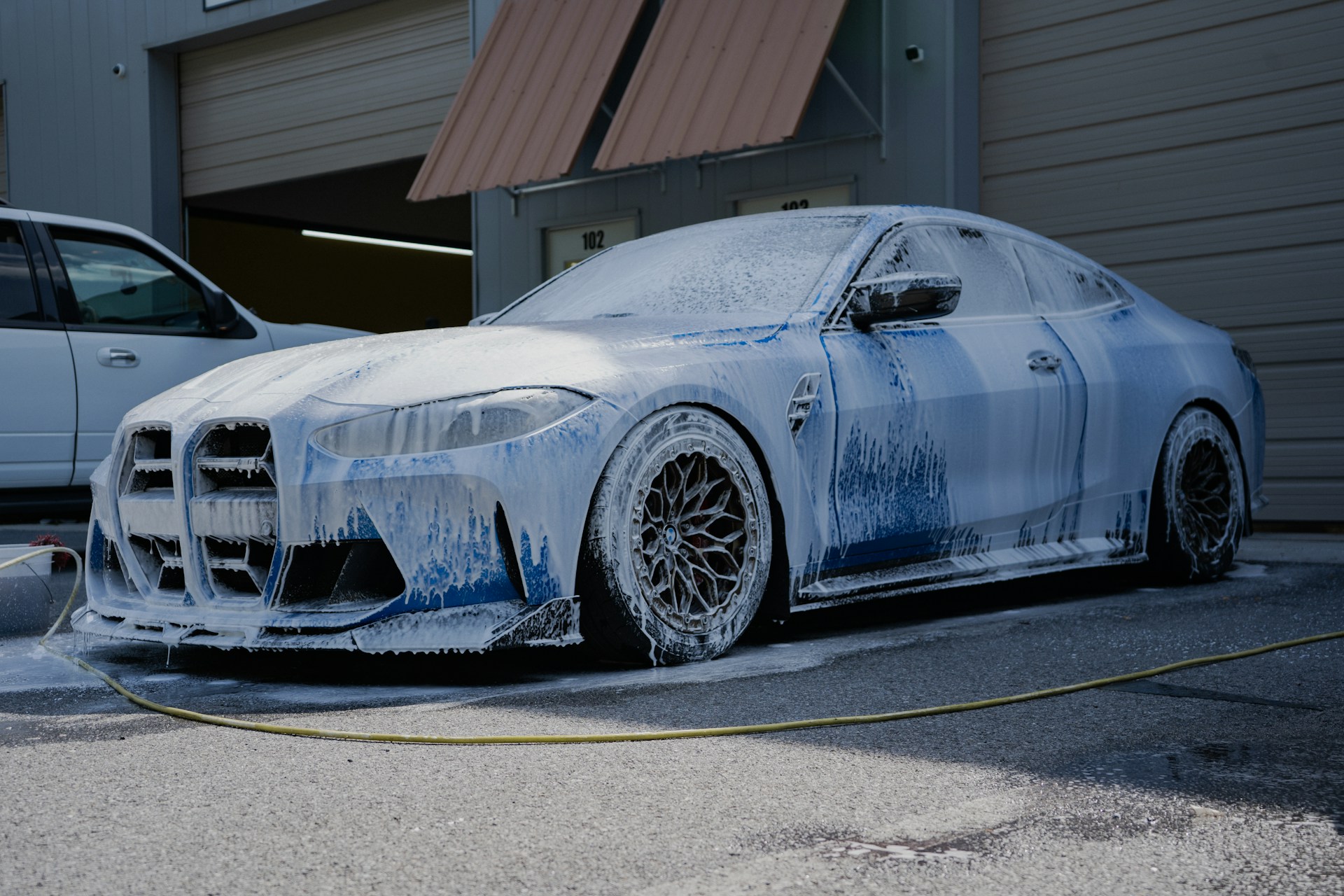 A blue car is covered in soap suds.