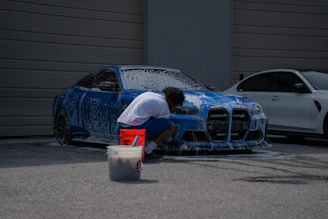 A person is washing a blue car with soap.