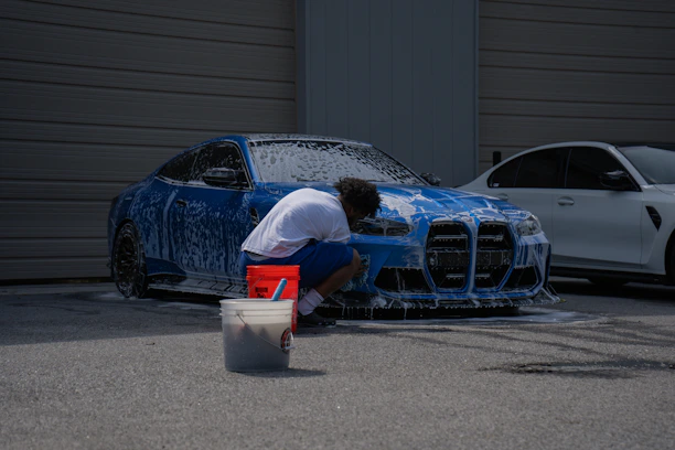 A person is washing a blue car with soap.