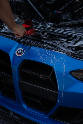 Washing a blue BMW car with a brush.