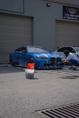 Man washes a blue sports car.