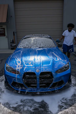A man is washing a shiny blue bmw.