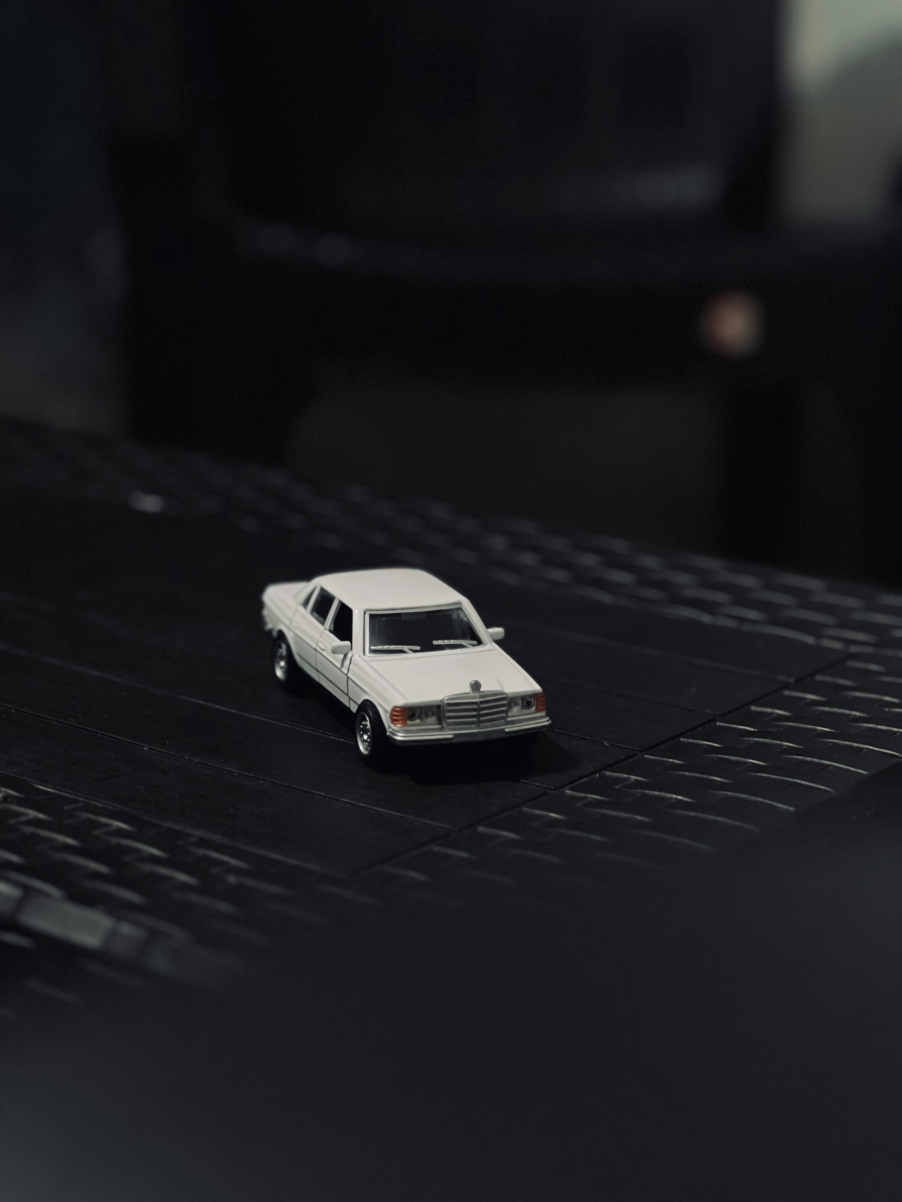 A white toy car sits on a black surface.