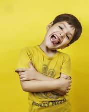 The happy boy grins broadly with his tongue out.