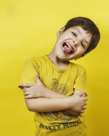 The happy boy grins broadly with his tongue out.