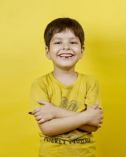 A happy boy smiles with crossed arms.