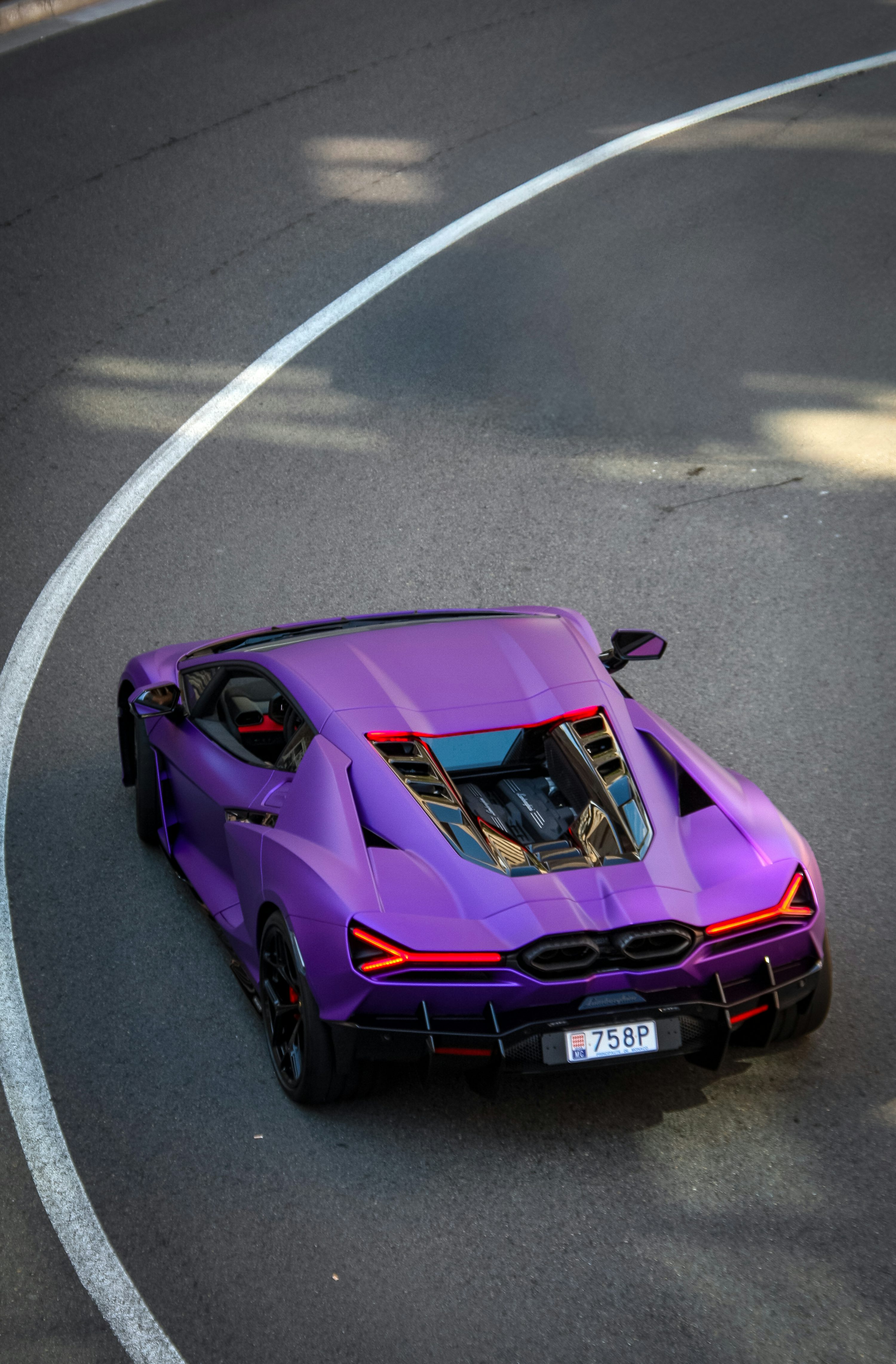 A purple lamborghini curves gracefully on the road.