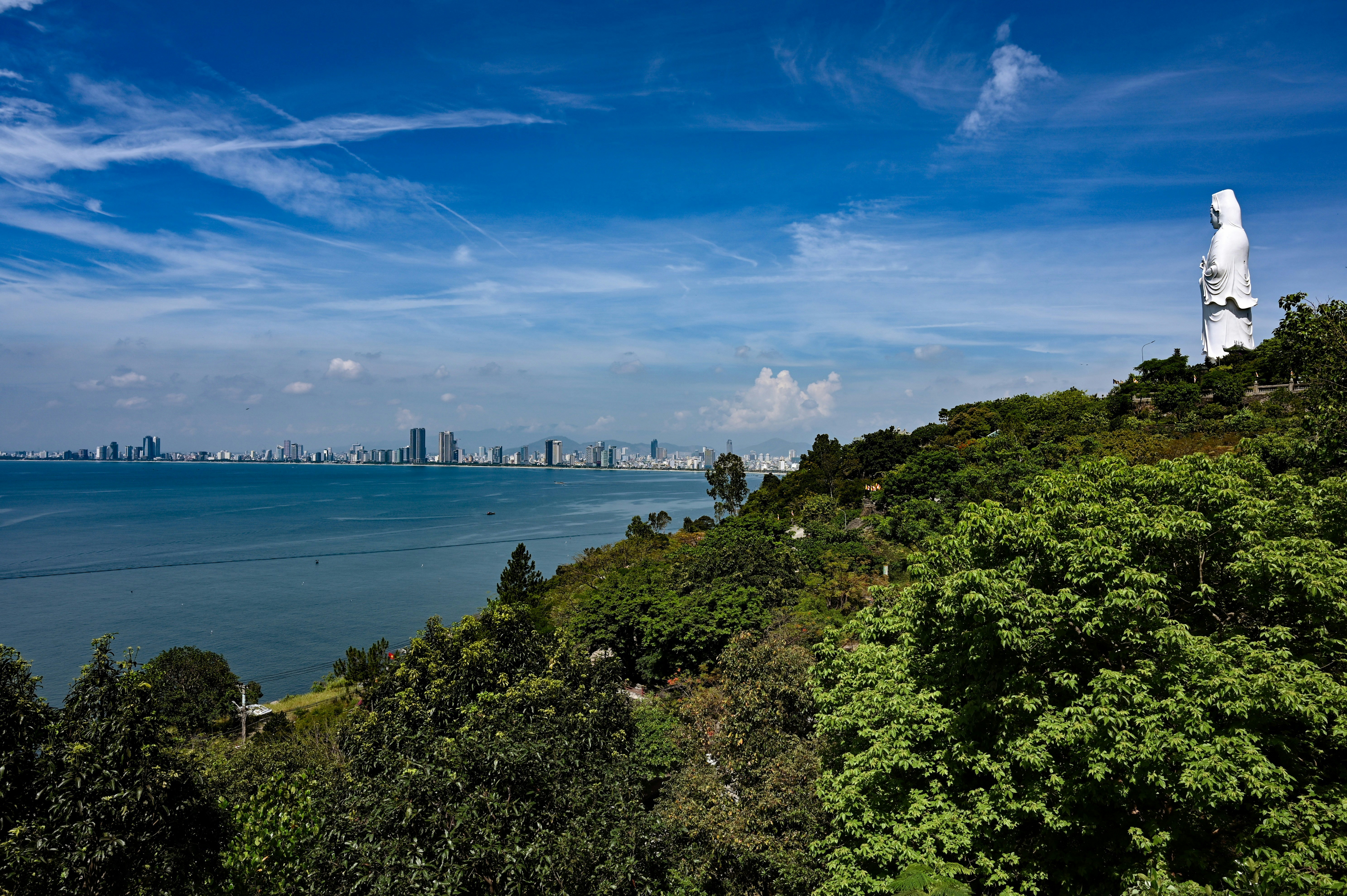 A coastal city view with a statue.