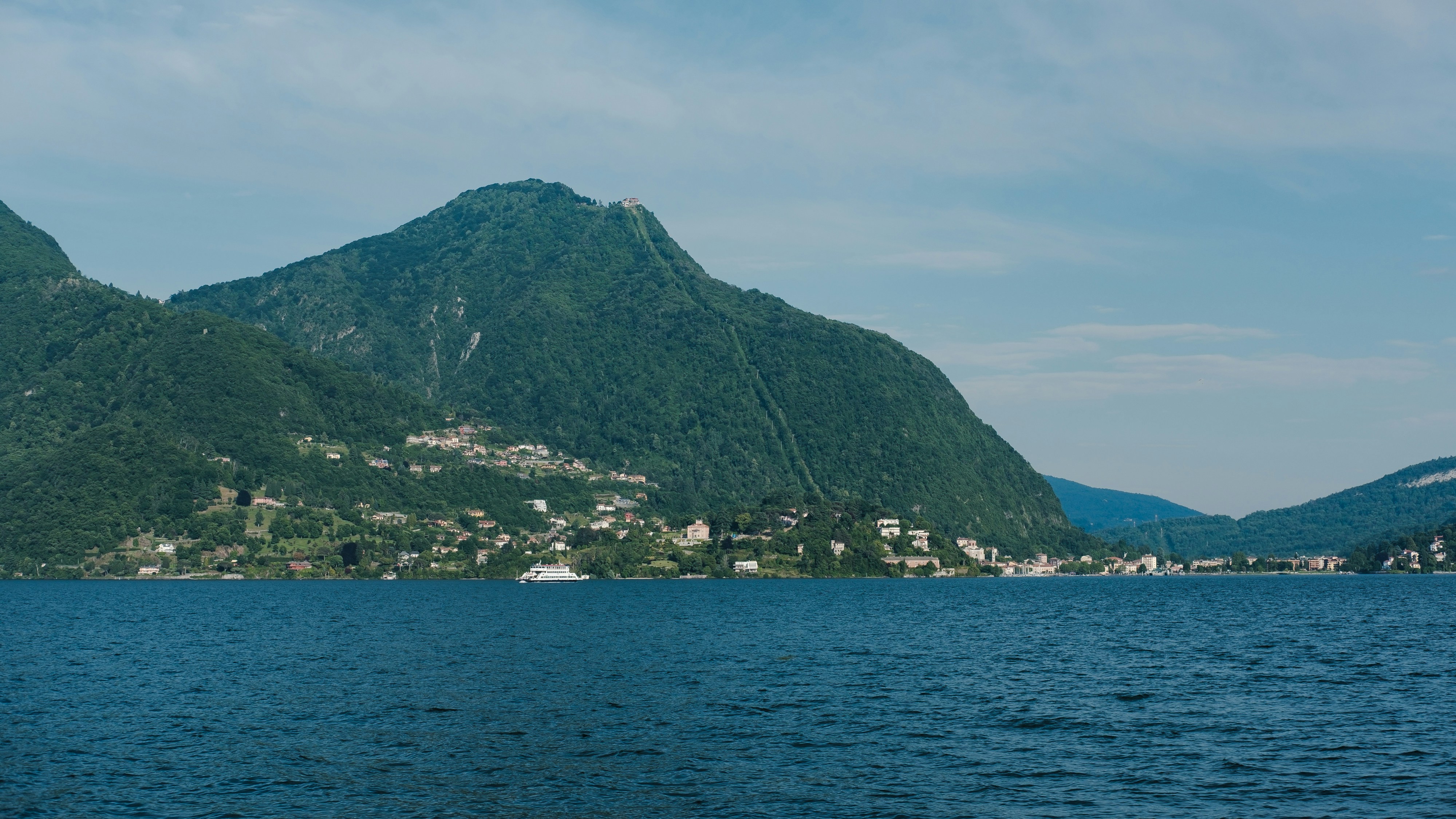 Mountains meet the sea under a blue sky.
