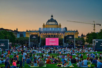 People watch a movie on a screen outdoors.