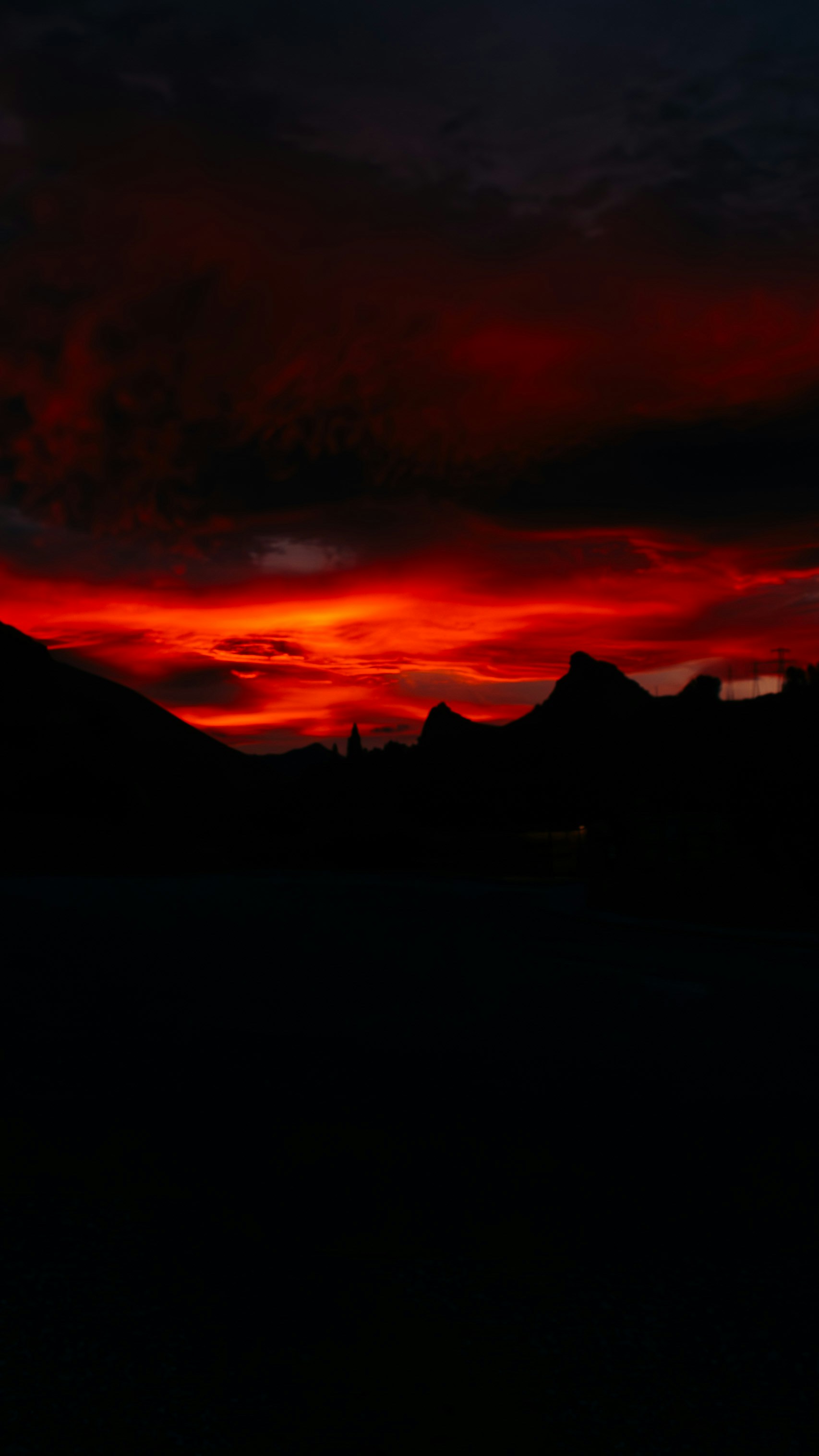 Red sunset over silhouetted mountains.