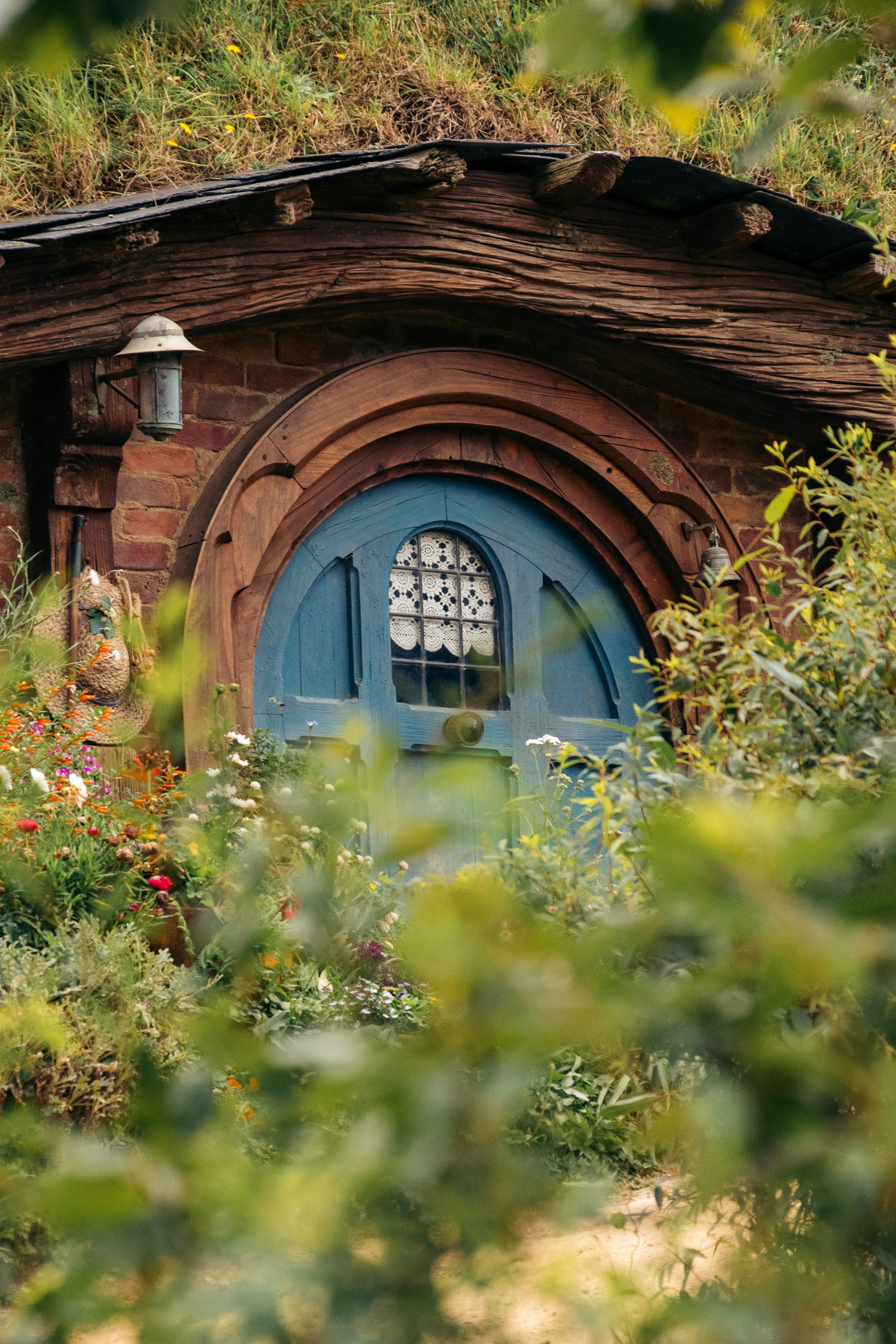 A hobbit hole with a blue door nestled in nature.