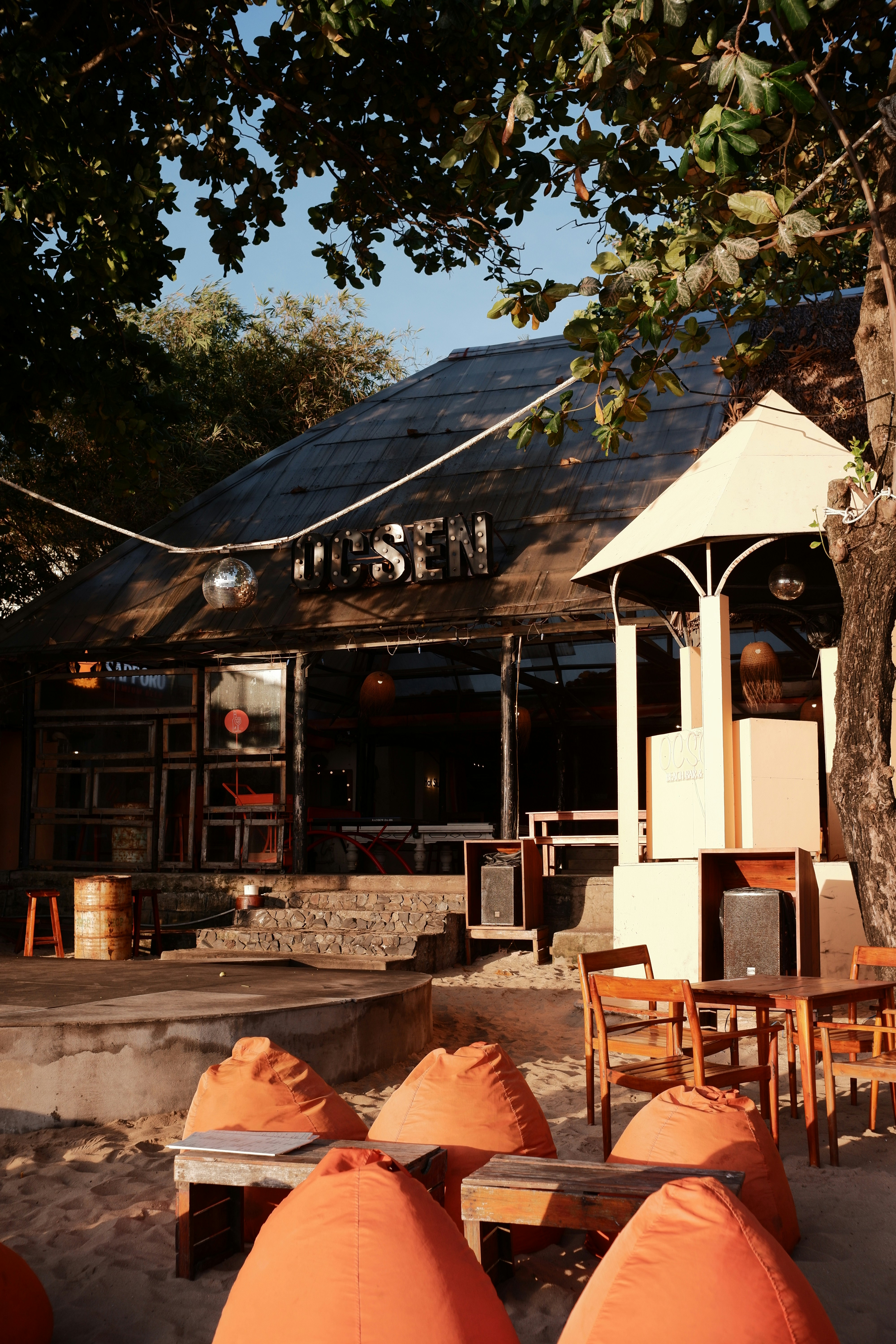 Um bar de praia com pufes e uma fachada charmosa