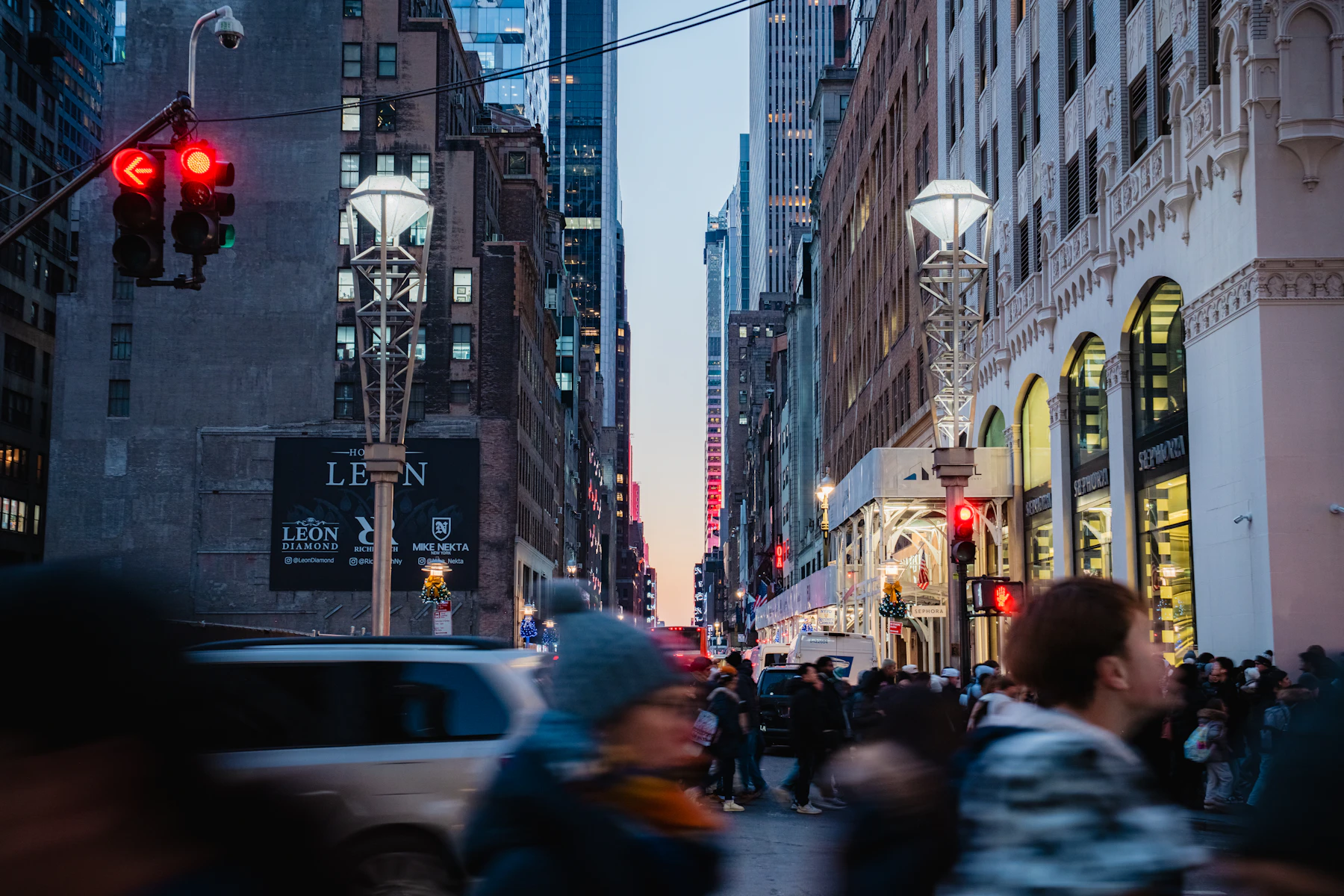 Busy Midtown Manhattan street at dusk with lit shop windows