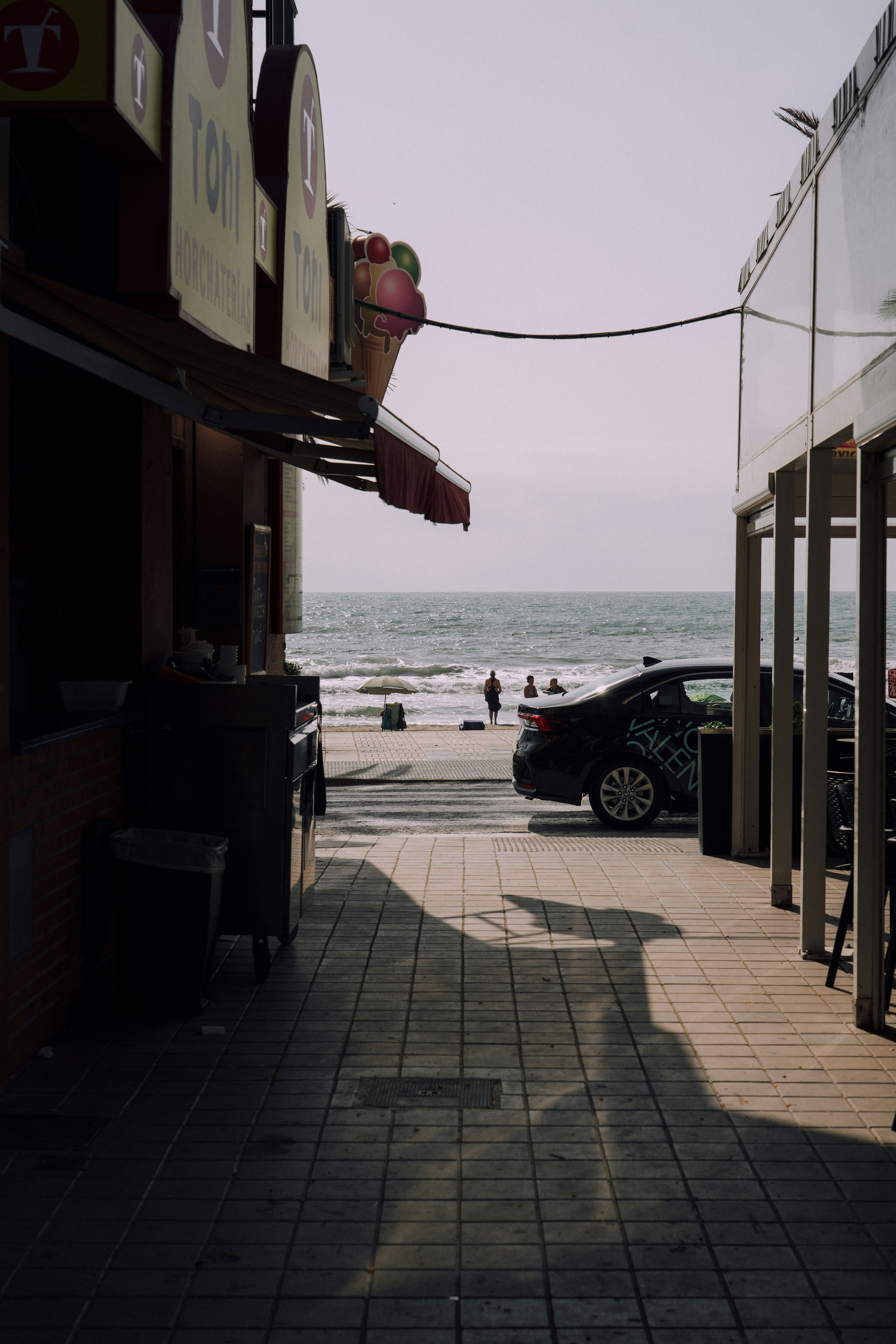 Pathway leading to the beach with shops on either side.