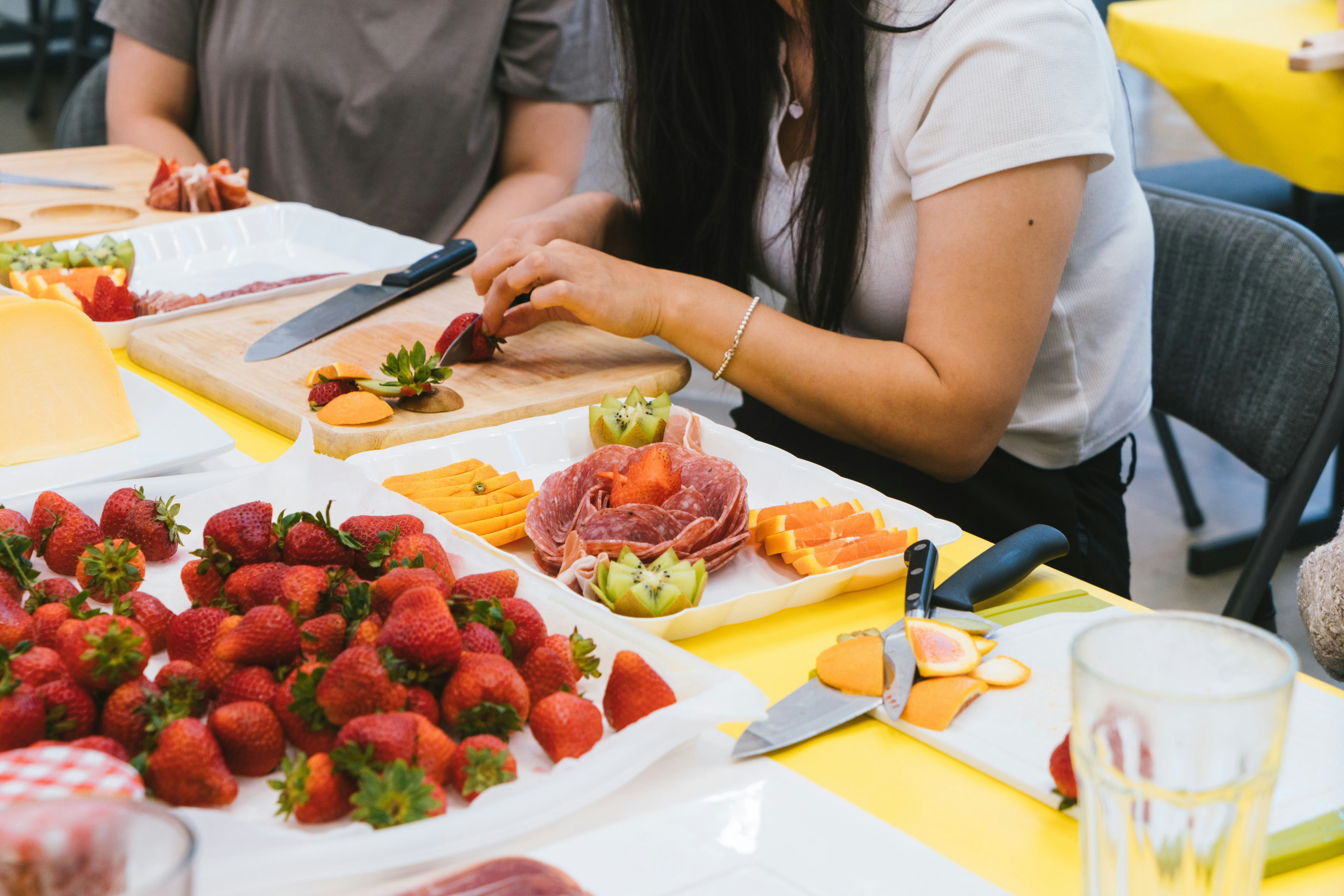 People prepare a charcuterie board with fruit.