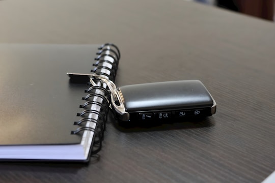 A car key lies next to a notebook.