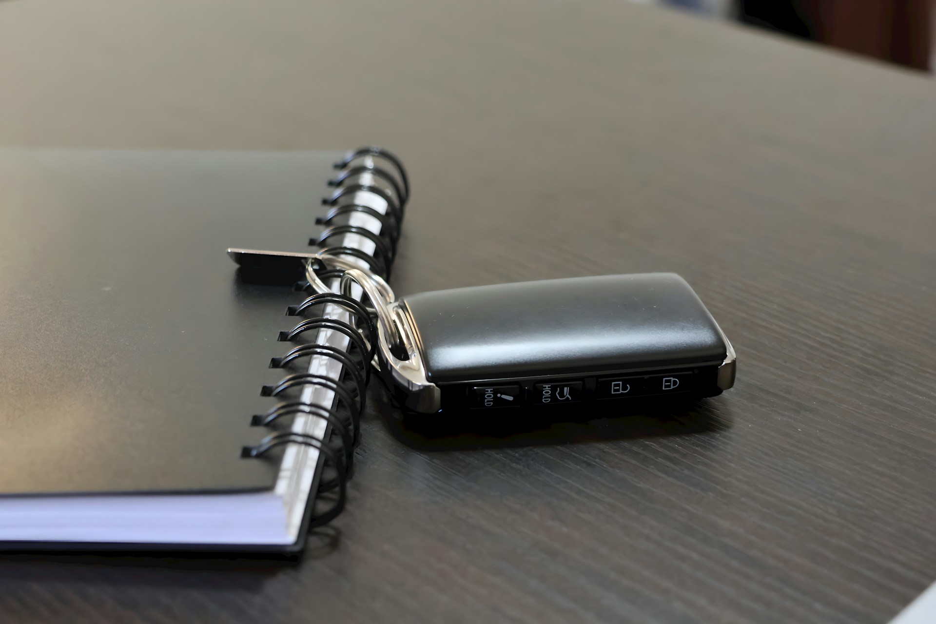A car key lies next to a notebook.