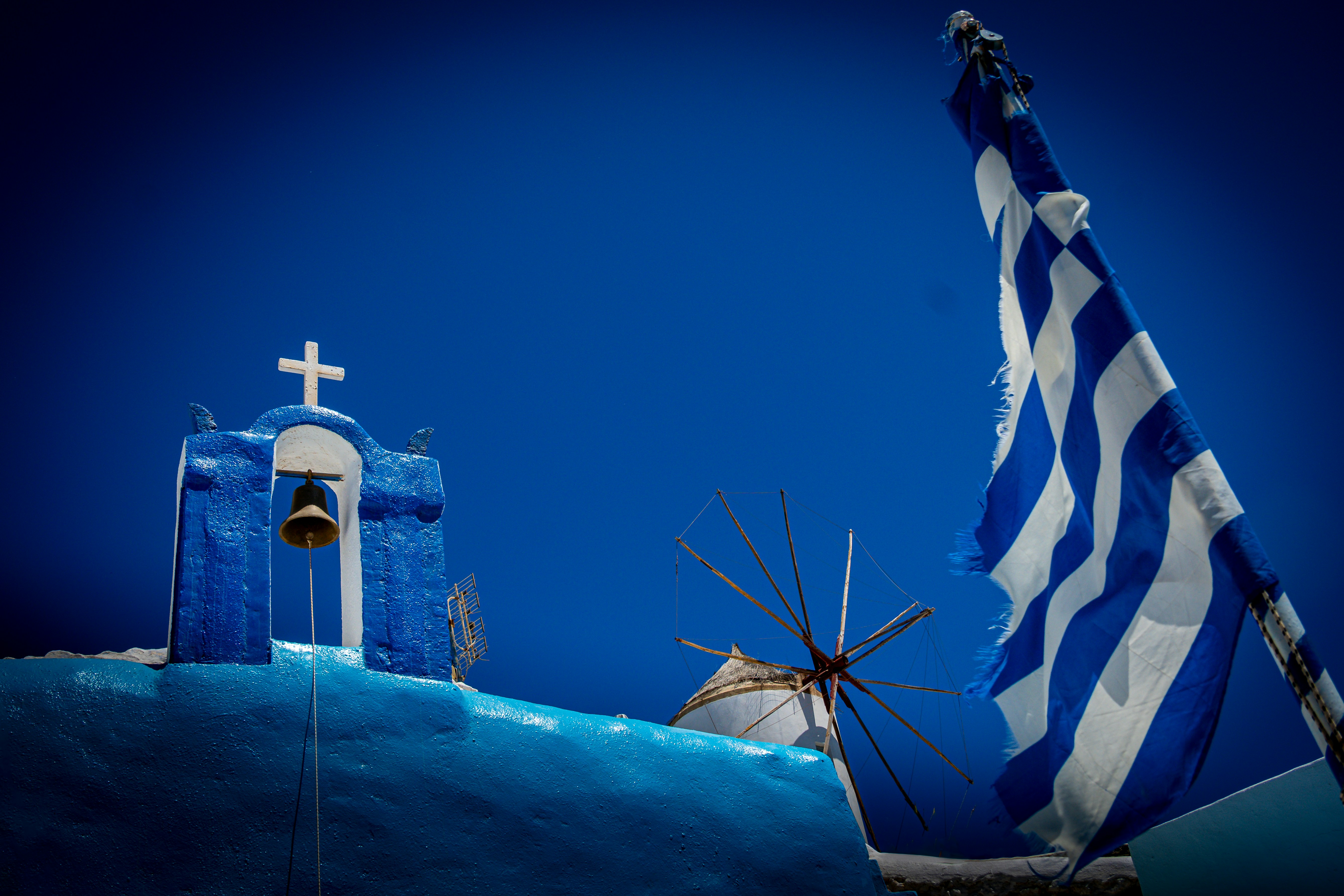 Greek scenery: church, windmill, and flag.