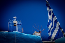 Greek scenery: church, windmill, and flag.