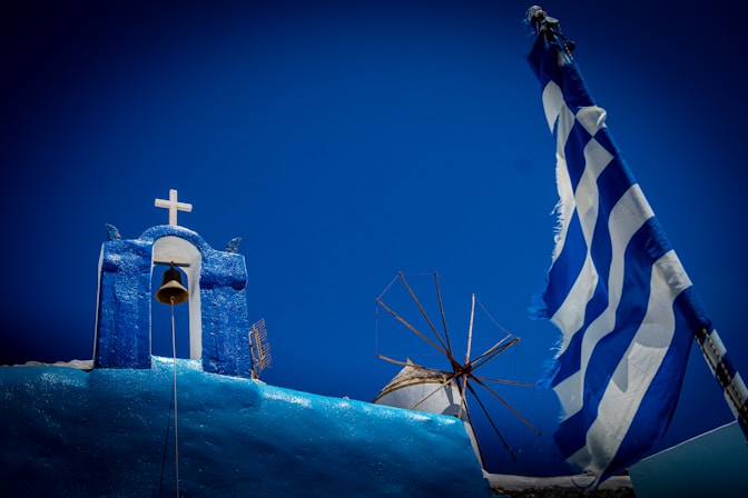 Greek scenery: church, windmill, and flag.