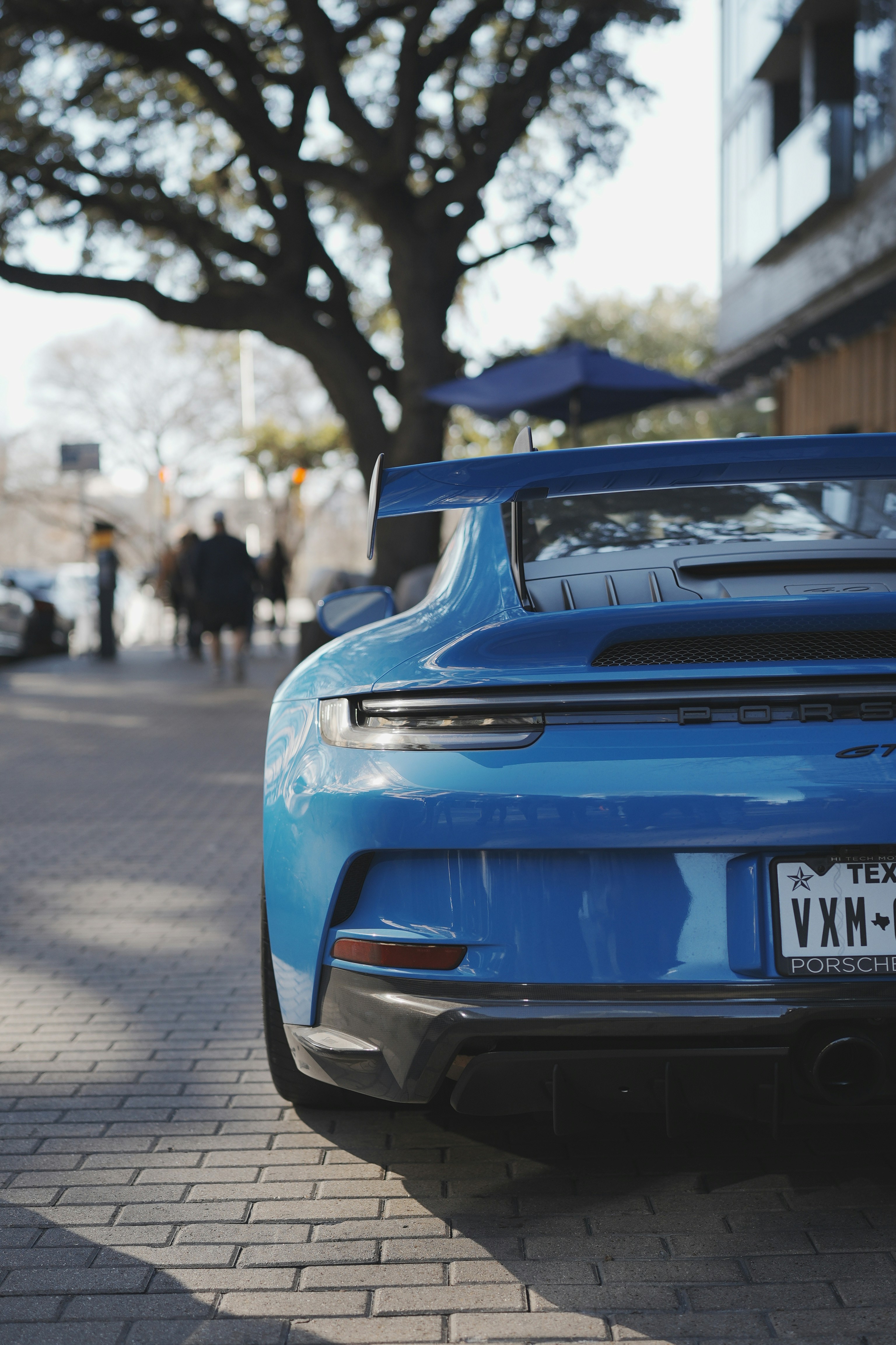 A blue porsche parked on a sunny street
