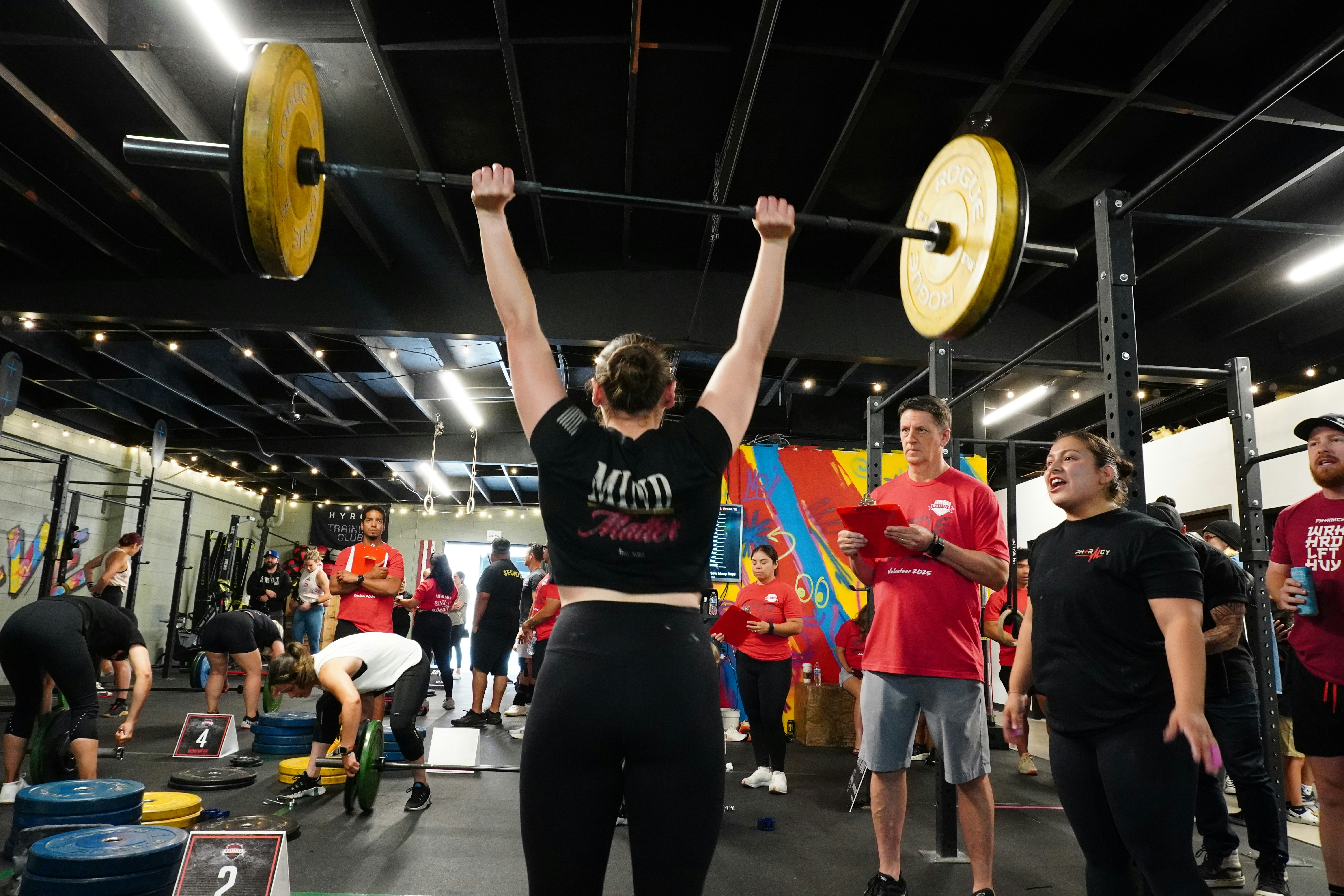 A weightlifter presses a heavy barbell overhead.