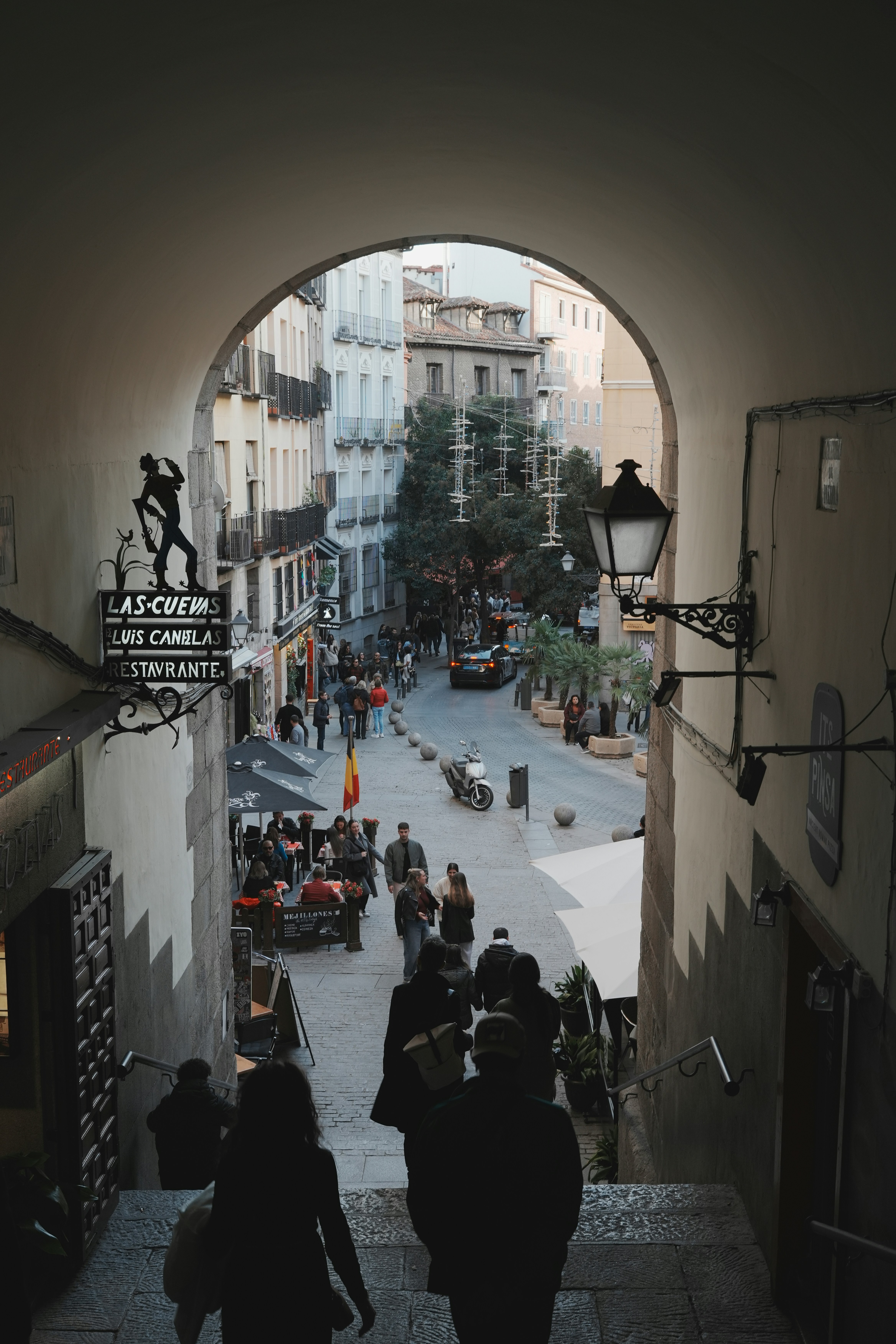People walk down stone stairs toward a bustling street