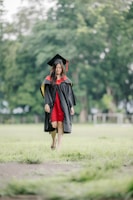 A graduate walks across the green field.