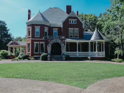 Red Victorian house in a leafy yard