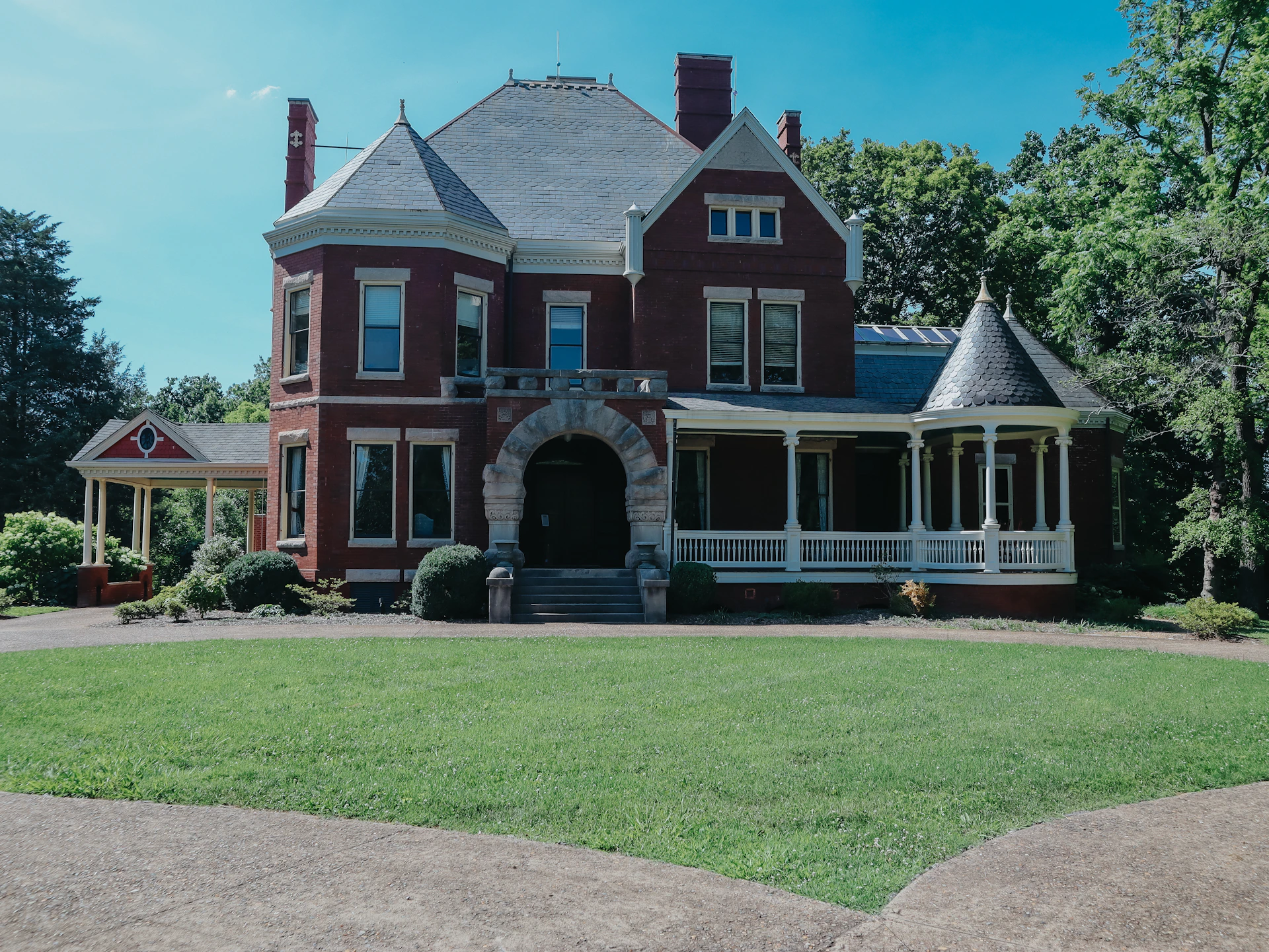 A large, red, victorian house sits in a yard.