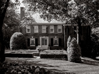 A brick house stands amidst lush greenery.