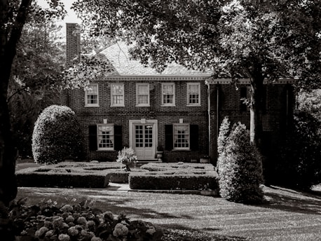 A brick house stands amidst lush greenery.