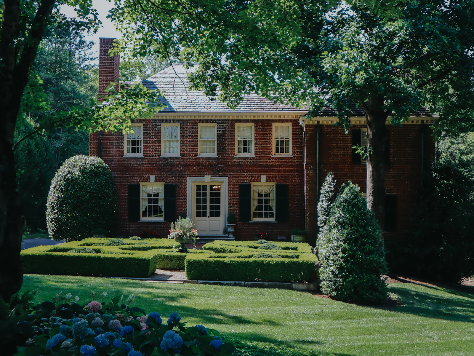 An older brick house with a mature garden.