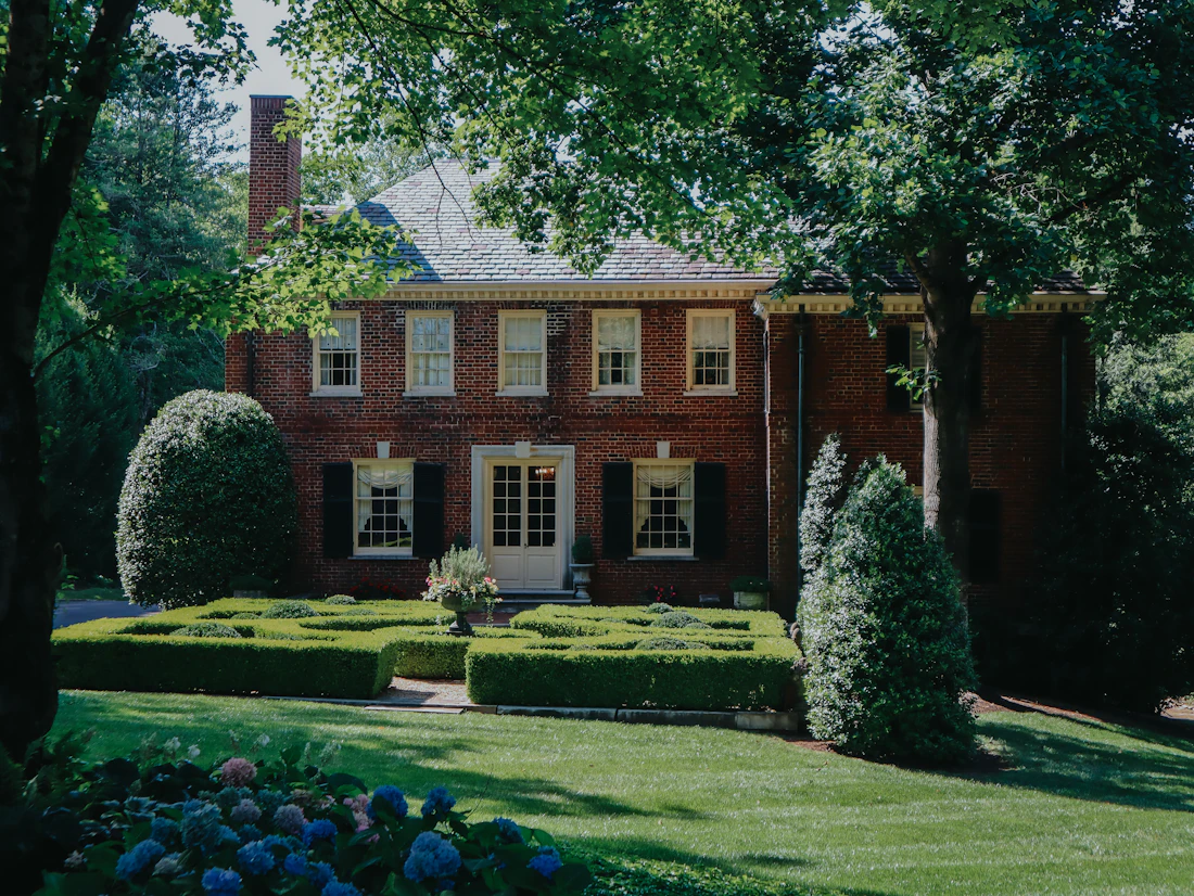 Brick Georgian home with sculpted boxwood landscaping