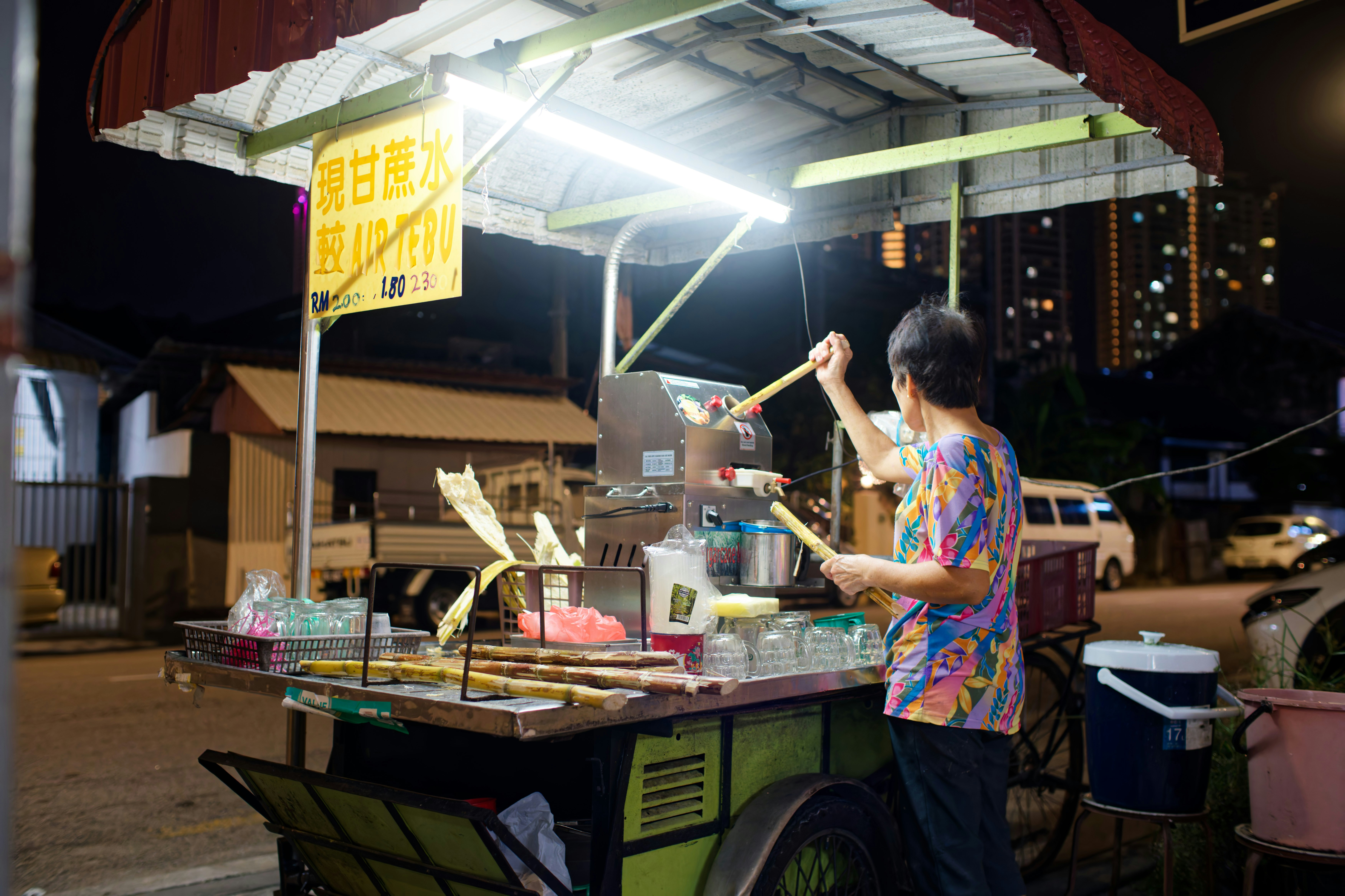 Person is making sugarcane juice at a street stall.