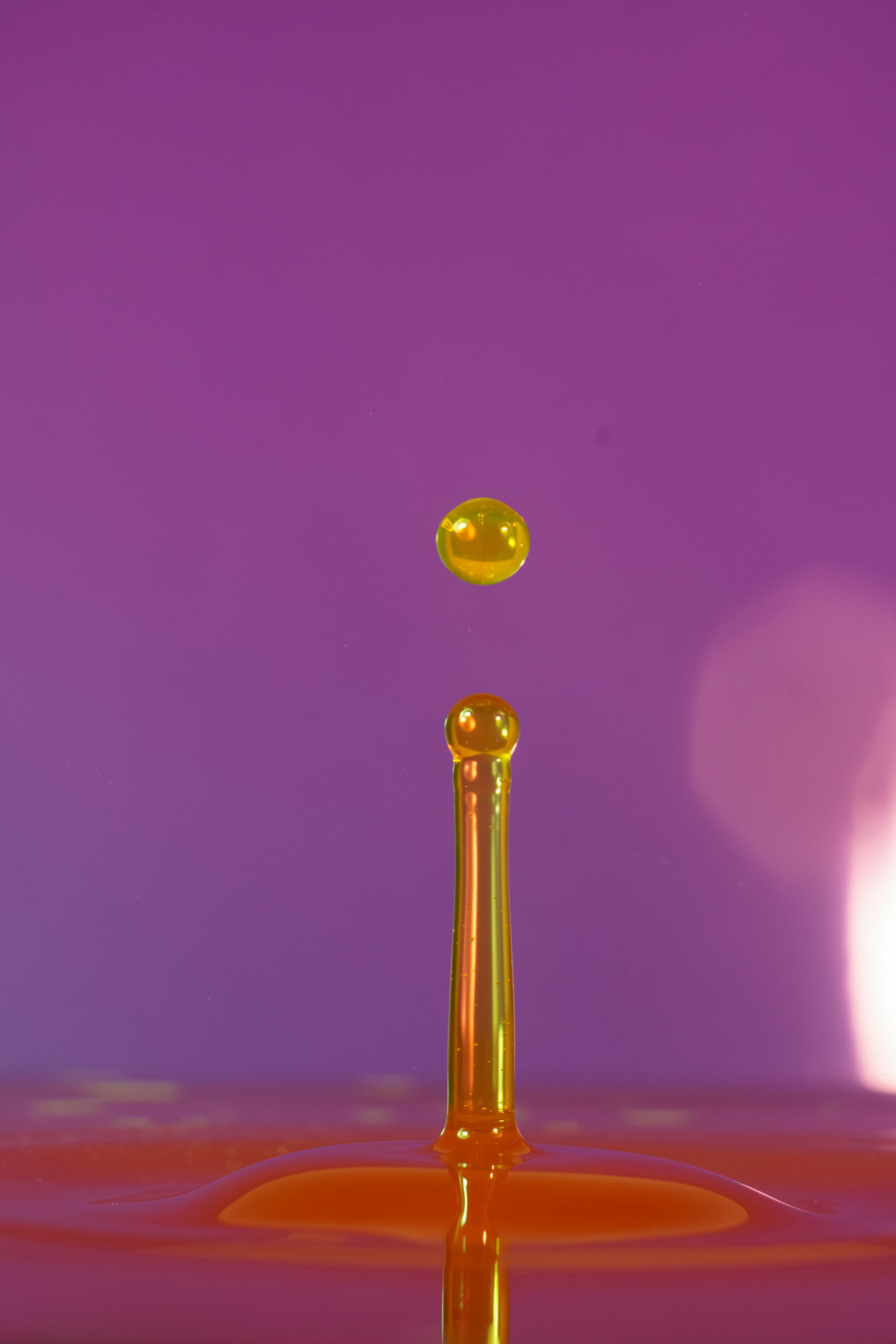A yellow droplet levitates above its source.