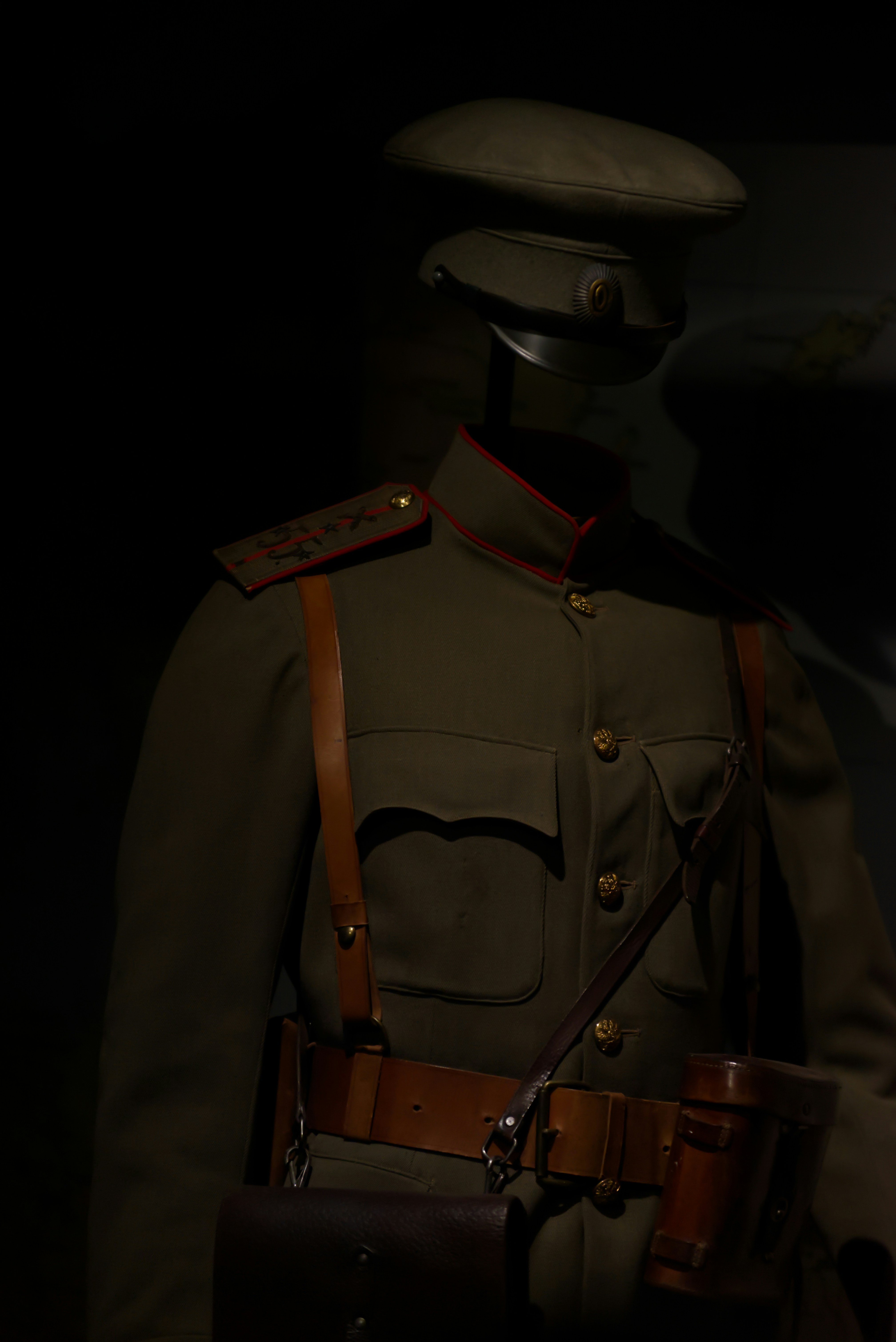 A military uniform displayed under dim lighting.