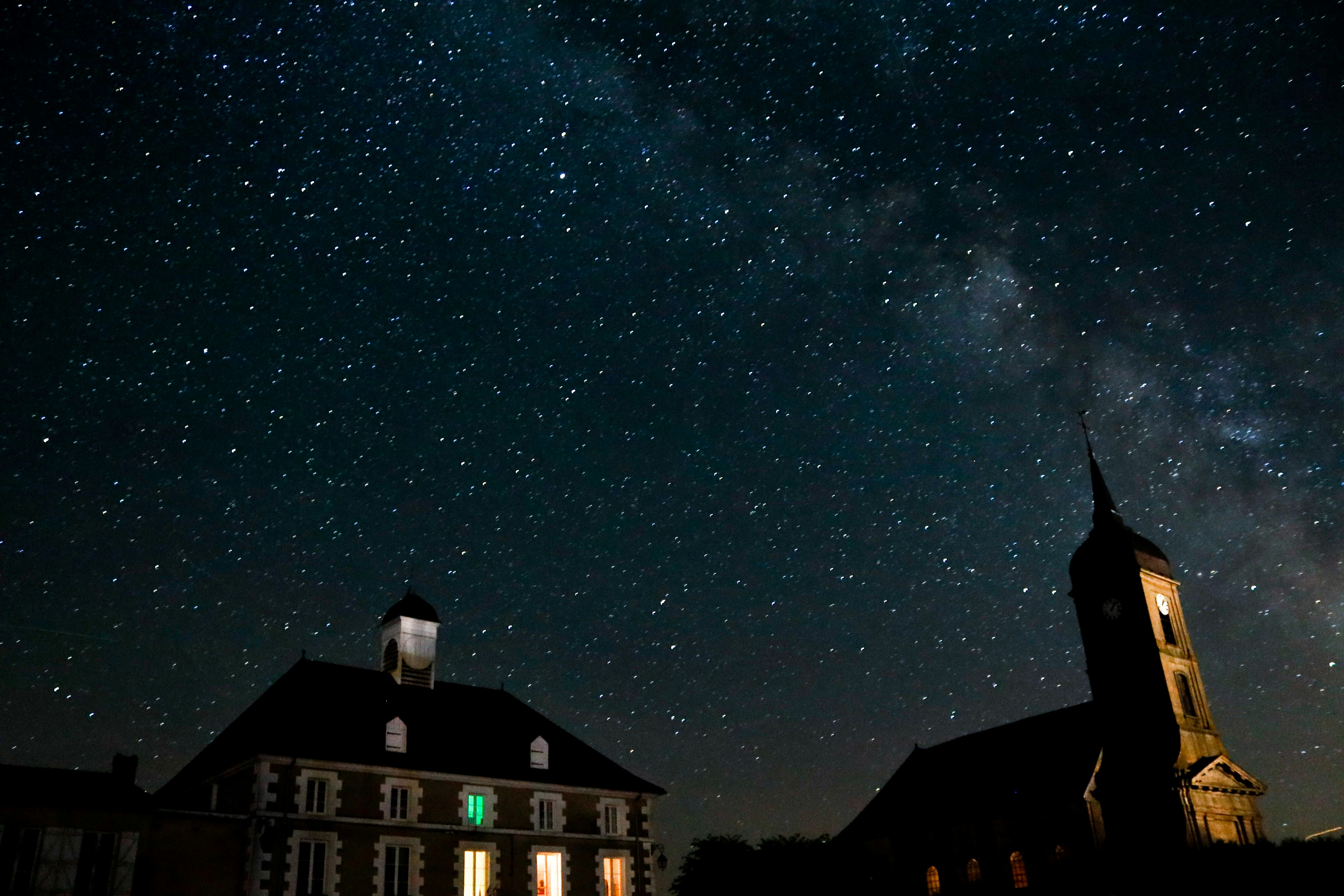Buildings stand beneath a stunning night sky.