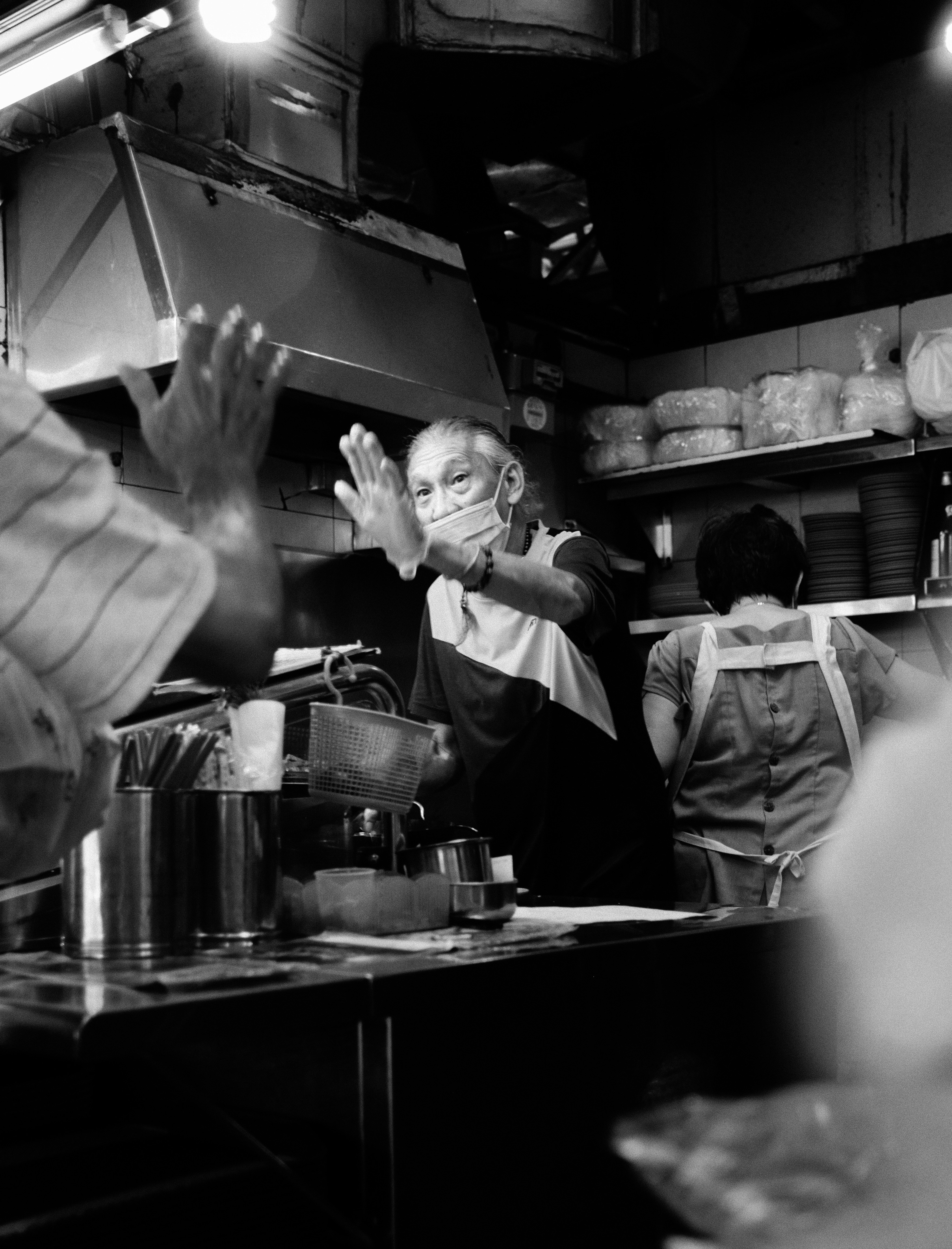 Un cuisinier salue d’une cuisine occupée.