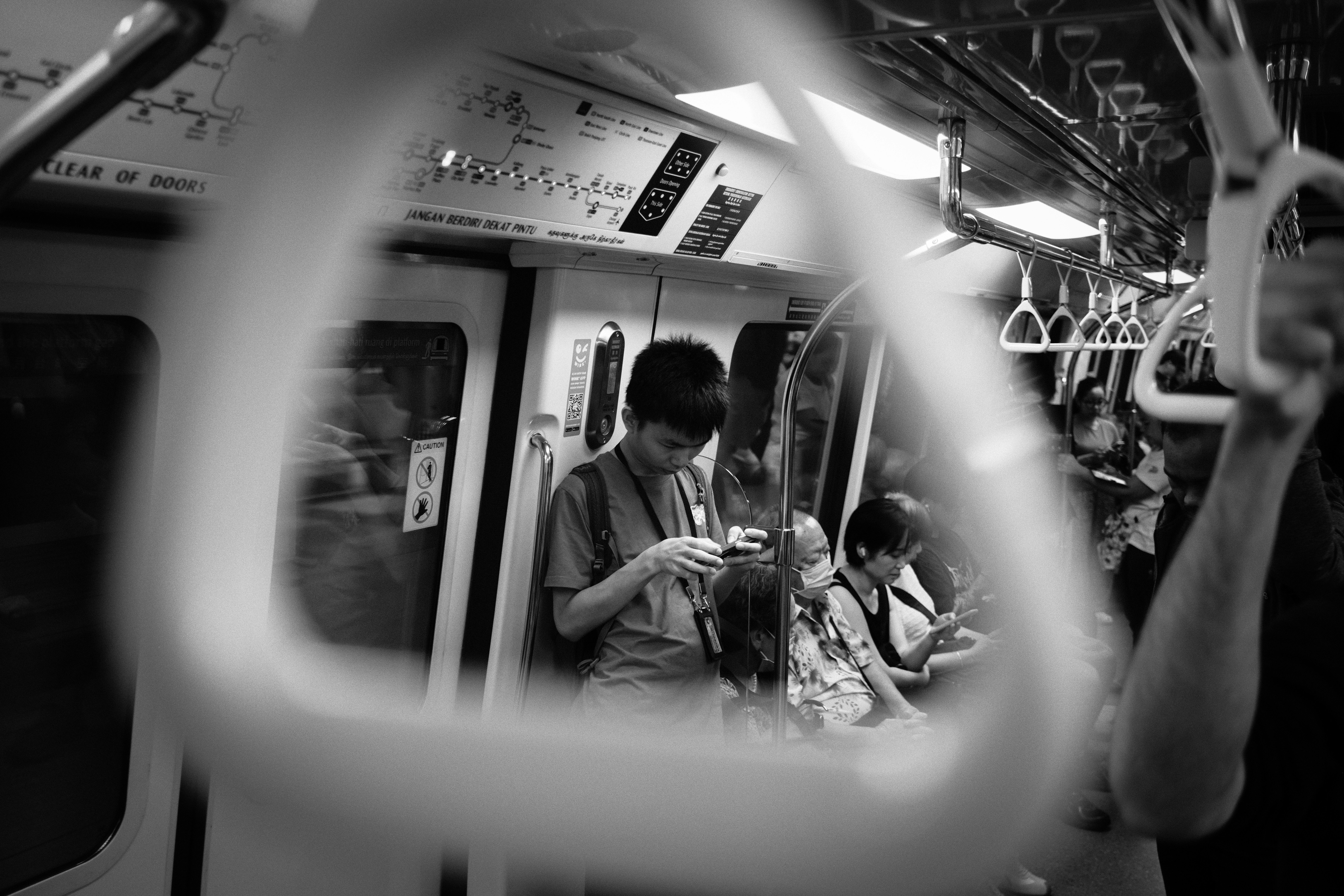 People riding a train, viewed through a handle.