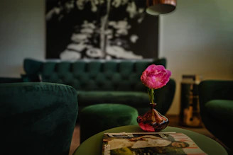 A pink flower sits on a coffee table.