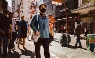 Woman wears a mask while walking in a crowded street.